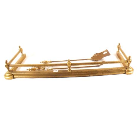 A brass fender plus a set of three brass fire irons