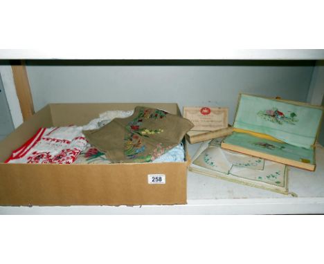 A box of vintage textiles including embroidered household linens. mats &amp; handkerchiefs