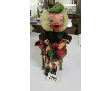 A vintage Scotsman puppet (no strings) sitting on a brass rocking chair.