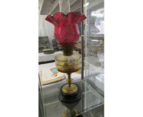A Victorian oil lamp with brass column, glass font and complete with burner, shade and chimney. ****Condition report**** Font