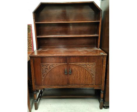 An oak dresser with canted two height shelf back and two cupboards below; a pedestal dinning table and four dinning chairs 