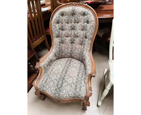A walnut framed spoon back nursing chair with carved detail with deep button back 