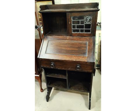 A Liberty's small oak bureau with open shelves and mullion glazed cupboard, folding side shelf, and wrought iron candle brack