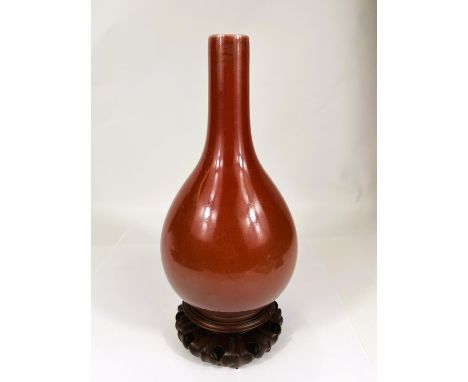 A Chinese oxblood glazed bottle vase, with seal mark to base, hard wood stand, height 32cm. In good condition.WE TAKE GREAT C