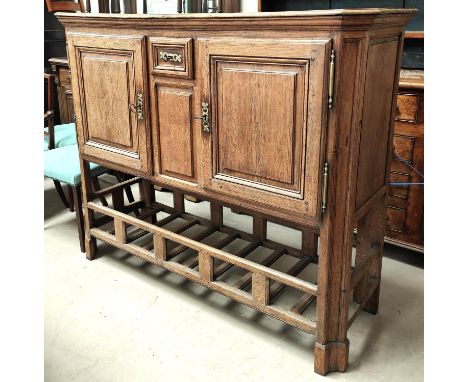 An oak country made side cabinet with double doors, panelled decoration, small central spice drawer with brass fittings, slat