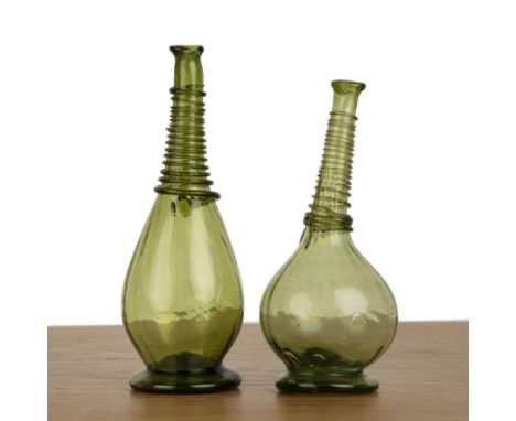 Two green glass flasksPersianeach with a reeded neck, 23cm and 25cm high  Chip to the underside of the base of one flask.