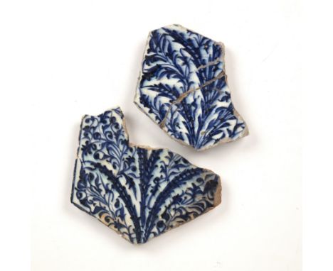 Two fragments of Middle-Eastern blue and white tilesdecorated in underglaze-blue with intricate designs of floral shrubs issu