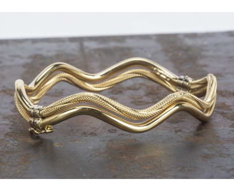 A Continental 18ct gold hinged bangle, with textured and polished double band decoration, bearing Continental strike marks to