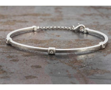 An 18ct white gold diamond set torque and chain bangle, the oval shaped bangle with chain clasp set with three small brillian