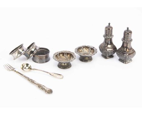 A small group of silver, including a pair of peppers, salts, a mustard spoon, three napkin rings and a fork