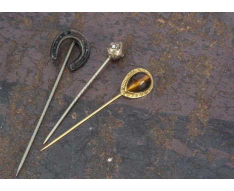 A yellow metal tiger's eye mounted stick pin, 6.2cm, 2.2g together with two late 19th Century white metal and base metal stic