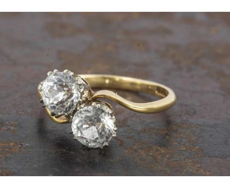 An 18ct gold zircon crossover dress ring, the round cut zircons in claw settings on a yellow gold shank marked 18ct, ring siz