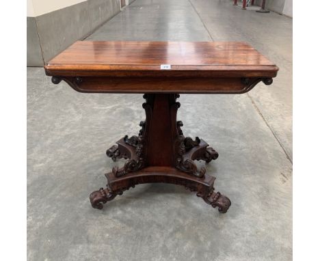 A 19th century rosewood card table, the fold-over green baize lined top on scroll and foliate carved square tapered column an