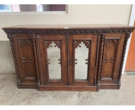 A 19th century oak gothic revival breakfronted side cabinet in the manner of Augustus Welby Longstone Pugin, the vine fruit c