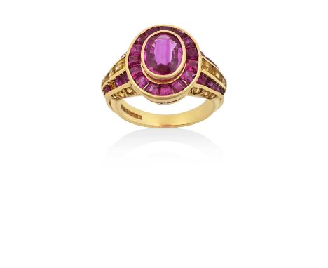 An 18 Carat Gold Ruby and Yellow Sapphire Cluster Ringthe oval cut ruby within a border of calibré cut rubies, in yellow rubb