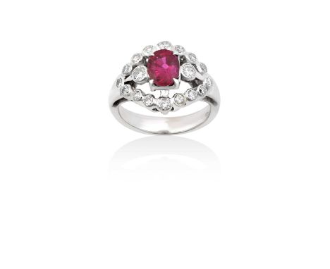 A Ruby and Diamond Cluster Ringthe oval cut ruby in a white claw setting, flanked by round brilliant cut diamonds, between tw