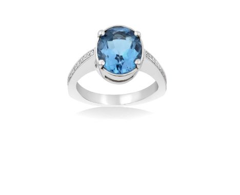  A Blue Topaz and Diamond Ringthe oval cut blue topaz in a white four claw setting, to eight-cut diamond set shoulders, on a 