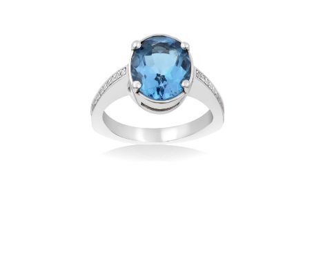  A Blue Topaz and Diamond Ringthe oval cut blue topaz in a white four claw setting, to eight-cut diamond set shoulders, on a 