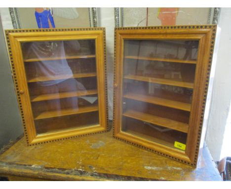 A pair of modern varnished light wood wall display cabinets, glazed with four internal shelves having a black painted diamond