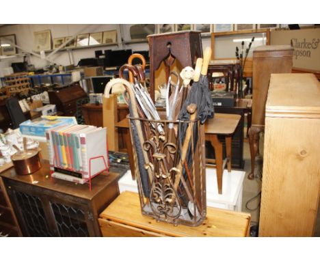A metalware stick stand and contents of walking sticks, umbrellas, shooting sticks etc.