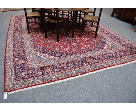 Kashan Carpet, the blood red field of palmettes and vines centred by an indigo and ivory medallion, framed by spandrels and i