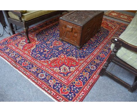 Tabriz Carpet, the indigo field centred by a raspberry and ivory medallion, framed by spanrels and indigo borders of palmette