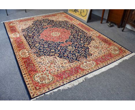 Machine Made Carpet of Oriental Design, the indigo field centred by a blood red cusped medallion framed by meandering vine bo