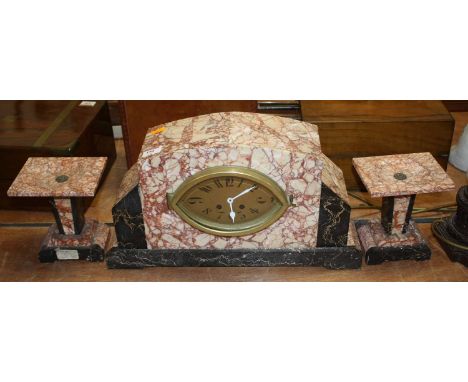 An Art Deco rouge and black marble cased clock garniture, the central clock having an oval brass dial with Arabic numerals an