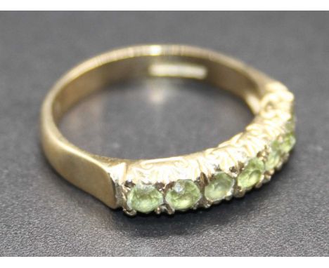 A modern 9ct gold and green peridot set half hoop ring, 2.5g, size M