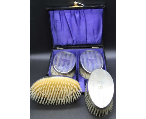 A pair of George V silver clothes brushes, each of oval form with engine turned decoration and in fitted leather case, togeth