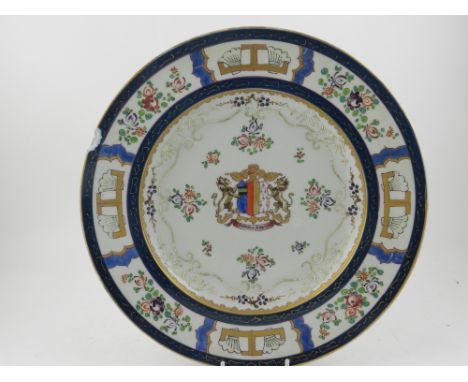 A Chinese hard paste porcelain dish, the edge having panels of flowers, the centre with armorial design above text 'Magnus Ha