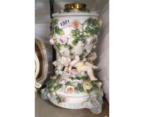 A 19th Century Sitzendorf porcelain oil lamp, the base with applied encrusted flowers and figures depicting cavorting putti w