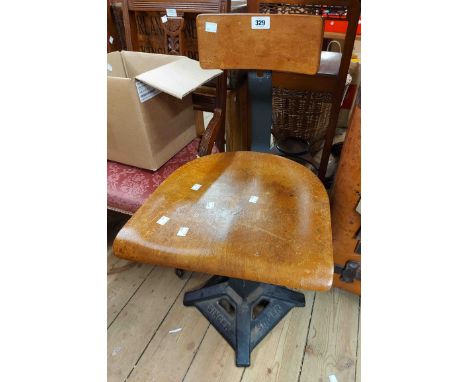 A vintage Singer sewing machine chair with laminated wood back and seat, set on a branded cast iron swivel base