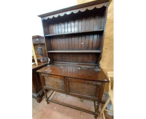 A 1.22m early 20th Century stained oak two part dresser with two shelf open plate rack over a double cupboard base with embos
