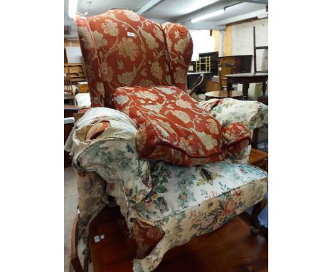 An old wing back armchair with floral tapestry upholstery, set on cabriole front legs