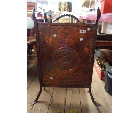 An Arts &amp; Crafts Movement copper firescreen with central repousse medallion depicting a fish swimming amidst seaweed, set