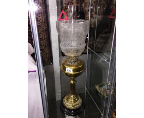 A brass oil lamp with etched shade.