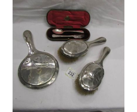 A cased silver spoon and fork, 2 silver backed brushes and a silver backed mirror.