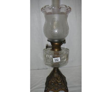An oil lamp with metal base, glass font and complete with shade.