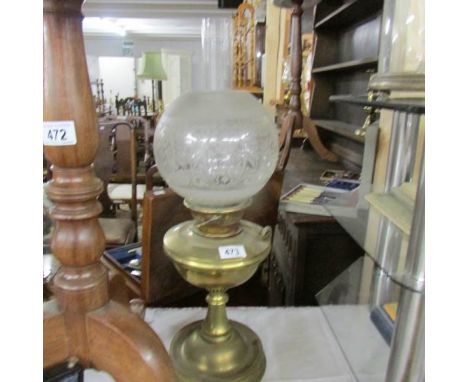 A brass oil lamp with etched glass shade.