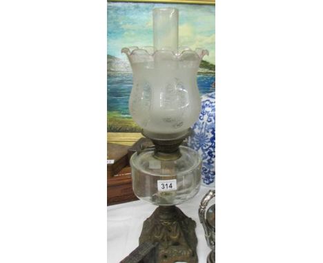 An oil lamp on metal base with glass font and etched glass shade.