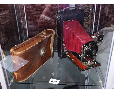 A leather cased Kodak folding camera.
