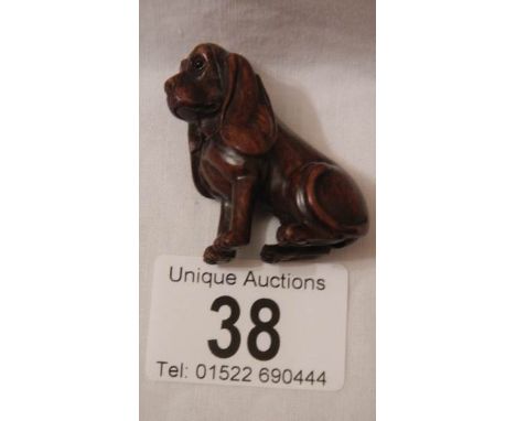 A carved rosewood netsuke as a dachsund, with small ivory disc inset, 2" tall, in good condition.