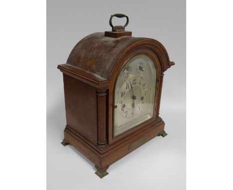 AN OAK ENCASED BRACKET-CLOCK having an arched silver dial with Arabic numberals and two subsidiary dials, presentation plaque