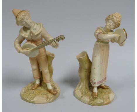 A PAIR OF ROYAL WORCESTER MUSICIAN SPILL-HOLDERS on naturalistic bases and stood against stumps playing tambourine and string