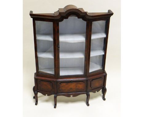 A MINIATURE MAHOGANY STANDING BIJOUTERIE CABINET having an arched glazed centre door flanked by two glazed panes on six bow s