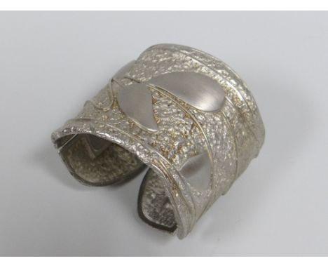 AN ALEXIS KIRK (1936-2010) WHITE METAL HINGED BANGLE WITH TEXTURED LEAF FINISH