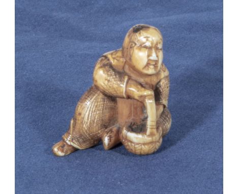 An antique netsuke depicting a man with small horn roundells onlaid on his head carrying a basket, 1.25"