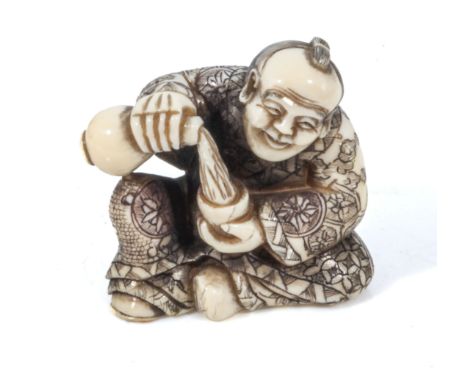 A fine quality antique Japanese mieji period carved ivory netsuke, depicting a Samurai drinking saki, dressed in fine robes w