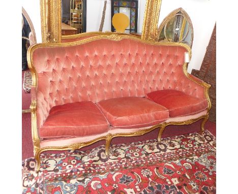 A Louis XV style giltwood three seater sofa with pink velour button back upholstery, raised on cabriole legs. 